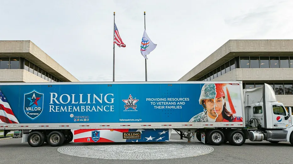 Semi Truck displaying Rolling Remembrance is parked in front of American flag.